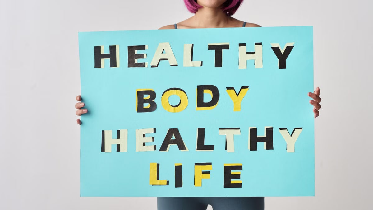 A woman holds a motivational poster advocating a healthy body and life for wellness.